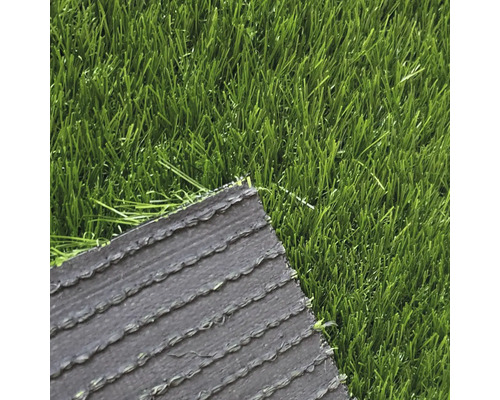 Detailní pohled na umělý trávník s viditelnou rubovou stranou a stébly.