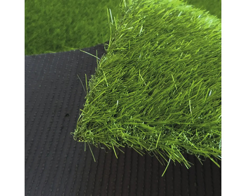 Detailní záběr na umělý trávník s hustými zelenými stébly a tmavou strukturovanou spodní stranou.