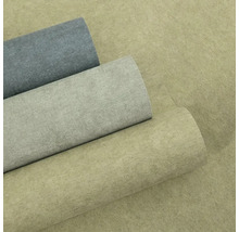 Tři role strukturované vliesové tapety v betonovém vzhledu v různých odstínech šedé a béžové.