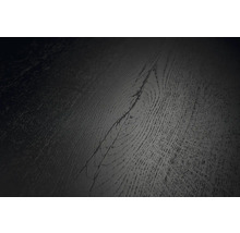 Detailní pohled na tmavý povrch podlahové krytiny s texturou dřeva a viditelným sukem.