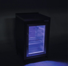 Malá lednice na nápoje s prosklenými dveřmi, modrým vnitřním osvětlením a kovovými policemi.