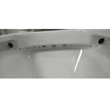 Detailní pohled na bílou keramickou záchodovou mísu se splachovacím kruhem a otvory pro distribuci vody.