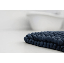 Tmavě modrá koupelnová předložka s žinylkovou strukturou před vanou.