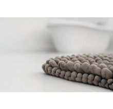 Detailní pohled na měkkou koupelnovou předložku s žinylkovou strukturou u vany.