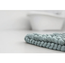 Detailní záběr na měkkou koupelnovou předložku z mikrovlákna s žinylkovou strukturou v koupelně před vanou.