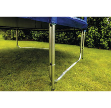 Detailní pohled na rám trampolíny s kovovými nohami ve tvaru U na trávníku v zahradě.