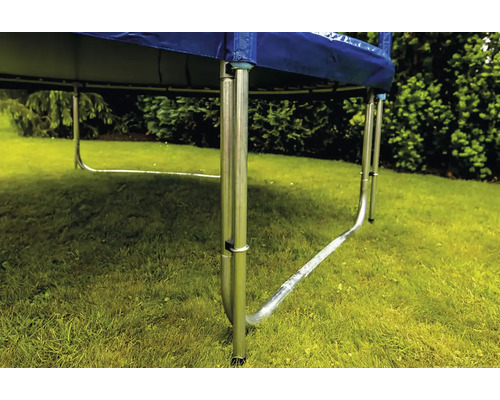 Detailní pohled na rám trampolíny s kovovými nohami ve tvaru U na trávníku v zahradě.