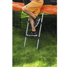 Kovový žebřík k trampolíně se dvěma plastovými stupni, připevněný k trampolíně na zahradě.