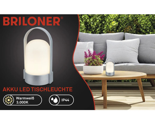 Logo Briloner, stolní LED lampa na akumulátor, teplá bílá 3000 kelvinů, IP44, přenosná s rukojetí, na zahradě na dřevěném stole.
