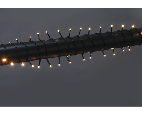 LED světelný řetěz s teple bílými diodami, omotaný kolem tmavé trubky.
