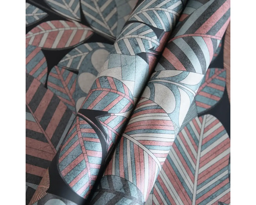 Detailní záběr na role tapety se stylizovaným vzorem velkých listů v terakotové, modré a krémové barvě na tmavém pozadí.
