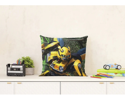 Čtvercový dekorativní polštář s postavou Transformers Bumblebee na bílé komodě v prosvětleném dětském pokoji.