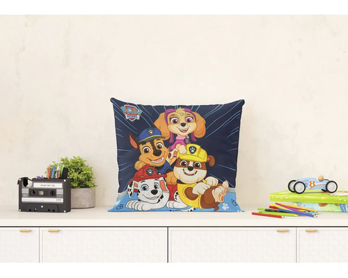 Světlá a uspořádaná scéna s čtvercovým dekorativním polštářem Paw Patrol s postavami Marshall, Chase, Rubble a Skye na psacím stole.