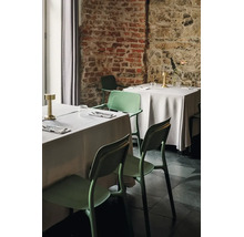Moderní zelené plastové židle s područkami u prostřených stolů v organizované restauraci s rustikálními cihlovými zdmi.