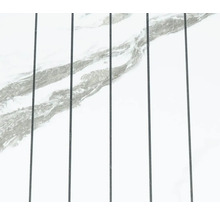 Bílý mramorový povrch s šedým žilkováním a svislými tmavými spárami.