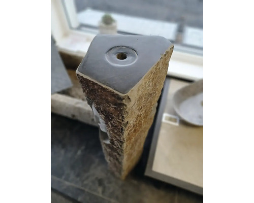 Detail horní části kamenného sloupu pro zahradní fontánu z přírodního kamene s leštěným povrchem a otvorem pro vodu.