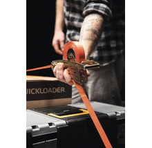 Osoba používající upínací popruh Quickloader s ráčnovým mechanismem k zajištění nákladu.