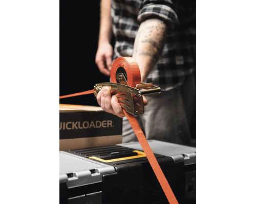 Osoba používající upínací popruh Quickloader s ráčnovým mechanismem k zajištění nákladu.