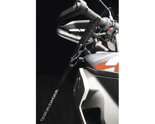Upínací popruh Quickloader připevněný k řídítkům motocyklu pro zajištění při přepravě.