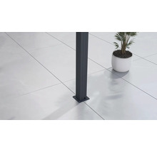 Detail antracitového sloupku s podlahovou deskou na světlé terasové dlažbě vedle rostliny v květináči.