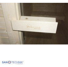 Madlo dveří sauny ze světlého dřeva s logem Home LUXE Sanotechnik, pohled na saunové lavice v pozadí, logo Sanotechnik.