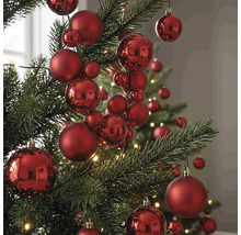 Červené vánoční koule různých velikostí s matným a lesklým povrchem na vánočním stromku.