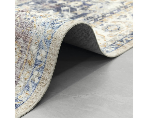 Detailní záběr na koberec s orientálním vzorem ve vintage stylu, s přehnutým rohem a pohledem na zadní stranu.