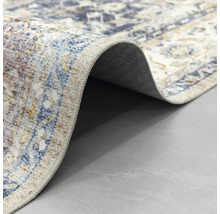 Detailní záběr na koberec s orientálním vzorem ve vintage stylu, s přehnutým rohem a pohledem na zadní stranu.