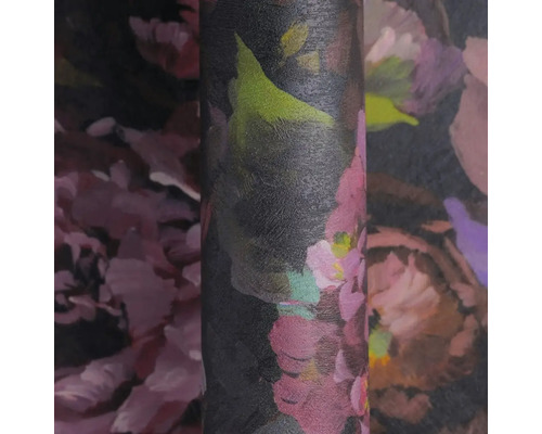 Detailní záběr na roli vliesové tapety s velkým květinovým vzorem v růžových, fialových a zelených tónech na tmavém pozadí, strukturovaný povrch.