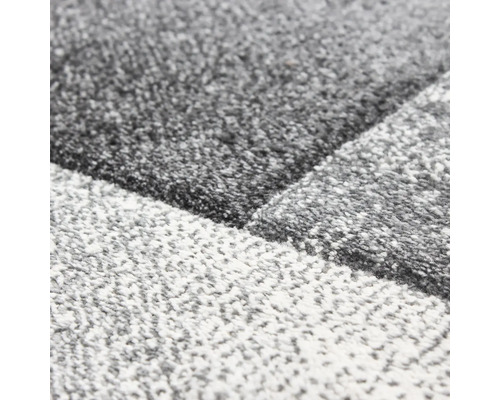 Detailní pohled na koberec s geometrickým vzorem a strukturovaným povrchem.