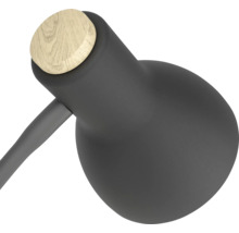 Hlava moderní stolní lampy z matného černého kovu s kulatým dřevěným detailem.