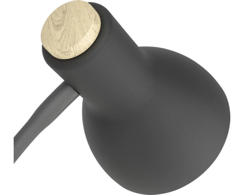 Hlava moderní stolní lampy z matného černého kovu s kulatým dřevěným detailem.