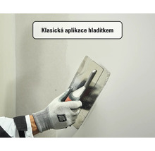 Klasická aplikace stěrky na stěnu pomocí nerezového hladítka.