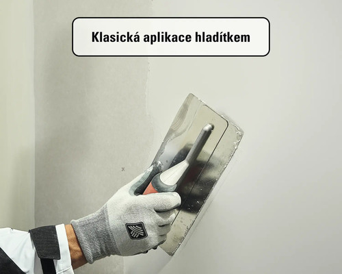 Klasická aplikace stěrky na stěnu pomocí nerezového hladítka.