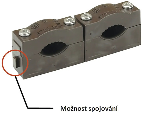 Dvě propojené plastové příchytky na trubky se šroubovým uzávěrem pro upevnění trubek.