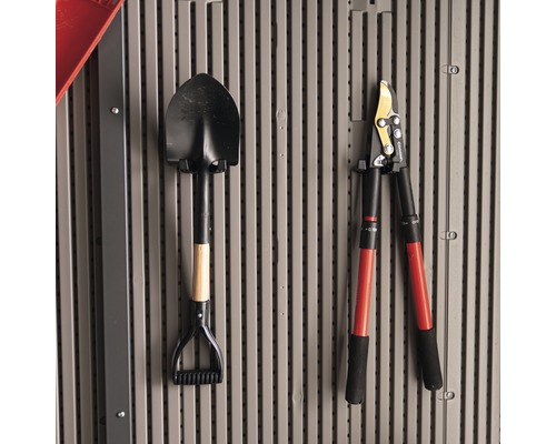 Na zdi visí rýč a nůžky na větve.