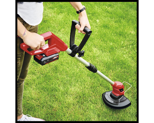 Pohled na osobu obsluhující akumulátorový vyžínač na zahradě