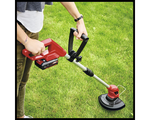 Pohled shora na osobu tlačící akumulátorový vyžínač na trávník