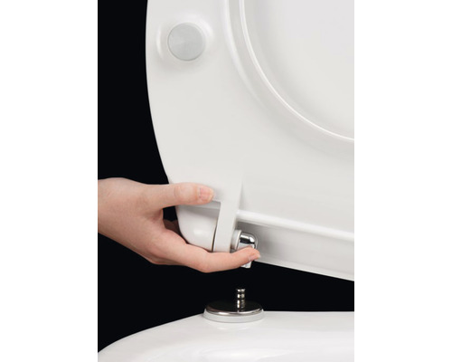 Ruka montuje záchodové sedátko na záchod.