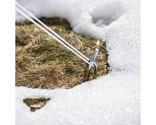 Kolík s napínacím lankem ve sněhu na trávníku