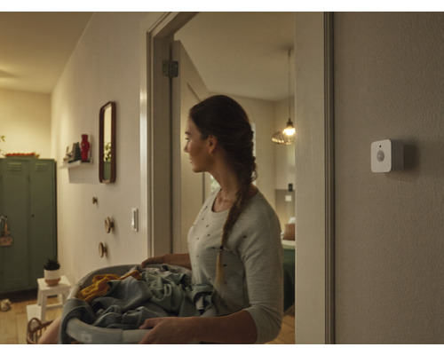 Žena s košem na prádlo na chodbě s pohybovým senzorem na zdi