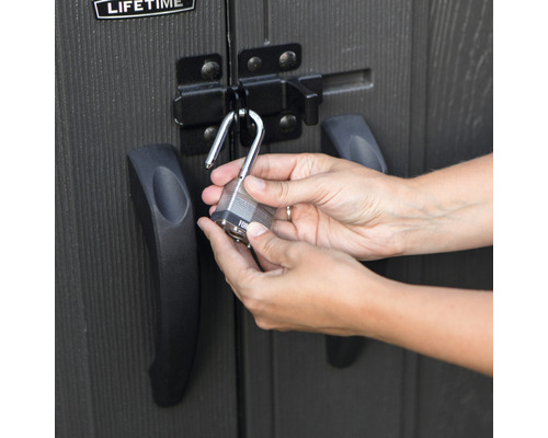 Osoba zamyká visací zámek na kůlně.