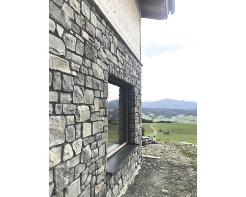 Venkovní pohled na dům s fasádou z přírodního kamene a oknem