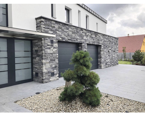 Fasáda domu s obkladem z přírodního kamene a garážovými vraty