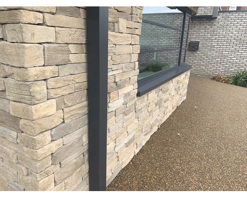 Detail fasády domu s kamenným obkladem a oknem