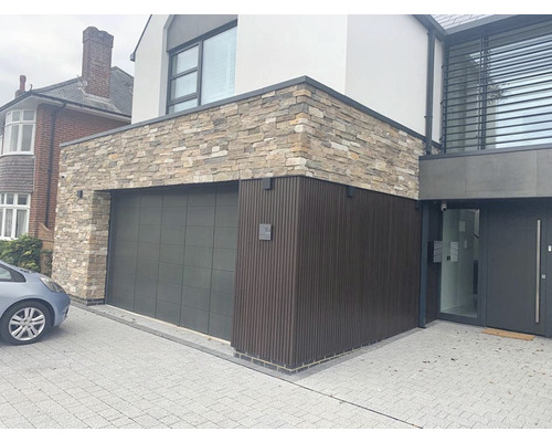 Exteriér moderního domu s garáží, kamennou fasádou a dřevěnými prvky