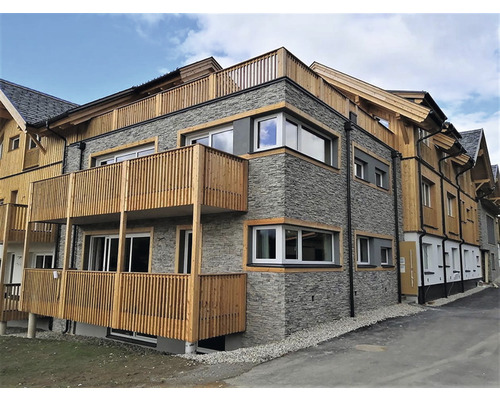 Vnější pohled na vícepodlažní budovu s dřevěnou fasádou a kamenným obkladem