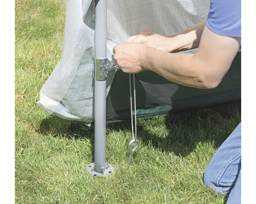 Detailní záběr osoby upevňující zahradní pavilon kolíky do trávy