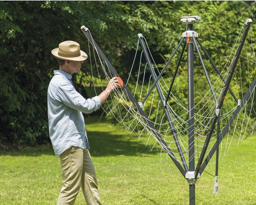 Muž obsluhuje venkovní sušák na prádlo na zahradě