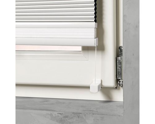 Detailní pohled na bílou plisovanou žaluzii na okně